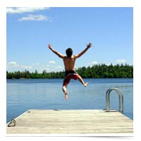 Happy kid jumping off a dock in summer.