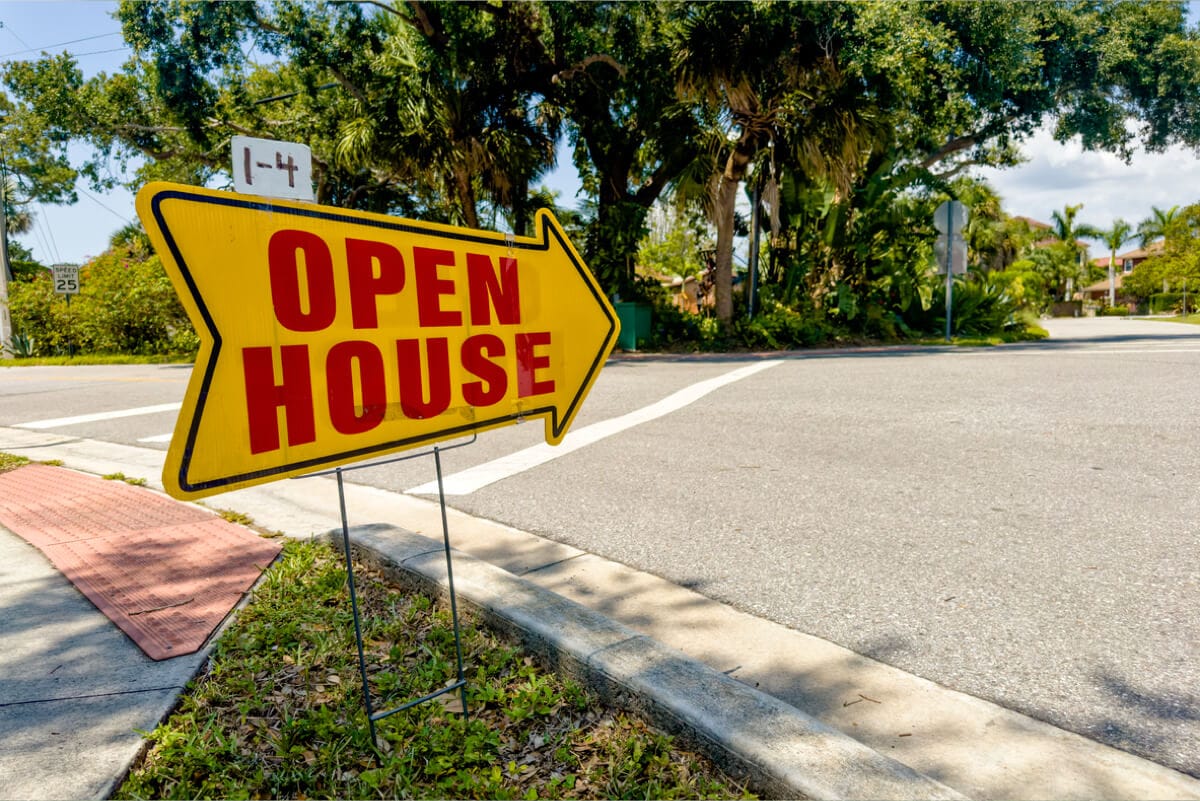 Yellow open house sign at residential street corner