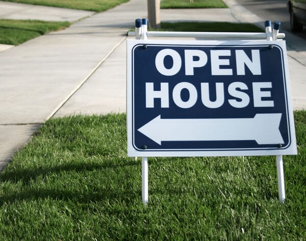 Open house sign with arrow on neighborhood lawn