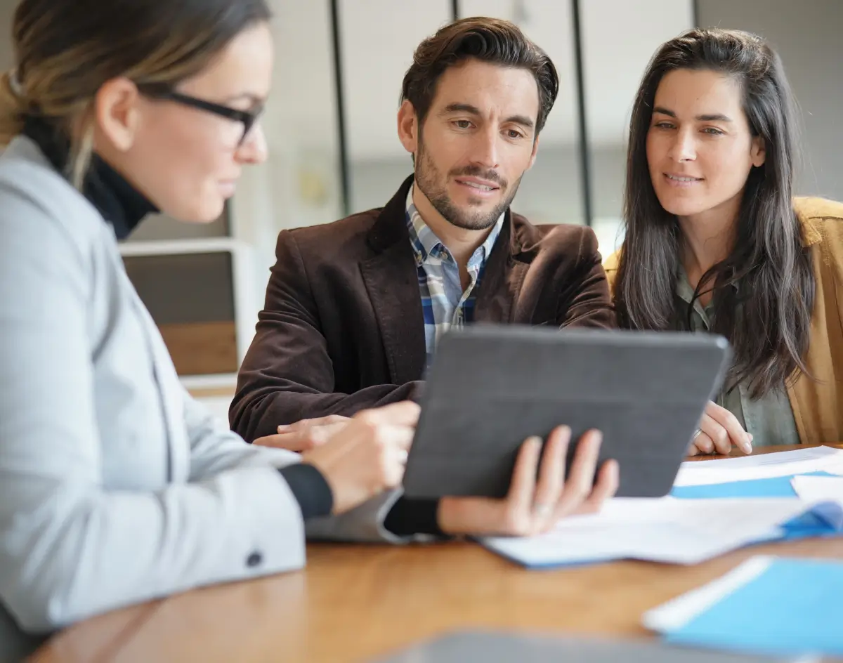 A realtor using a tablet to help clients during a meeting.