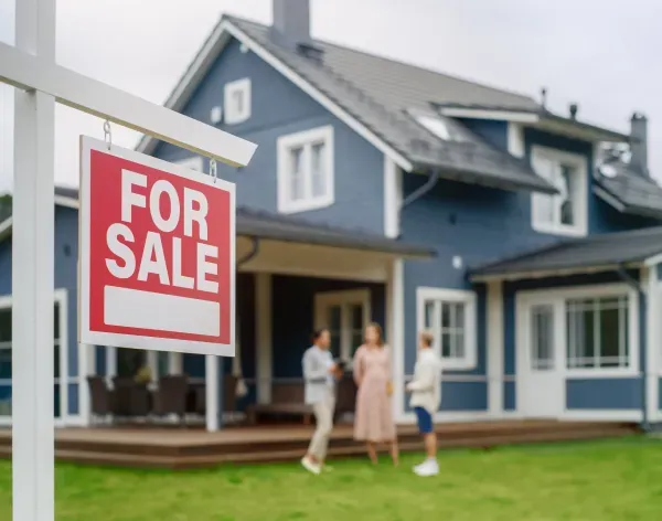 'For Sale' sign in front of a house with people in the background