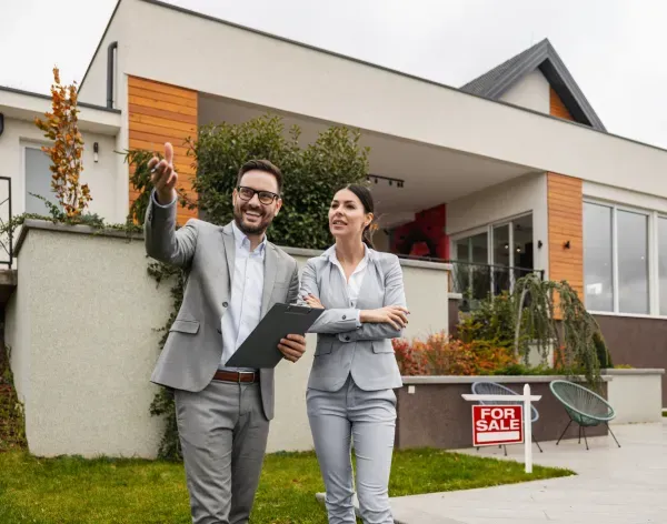 Realtors in front of a for sale property