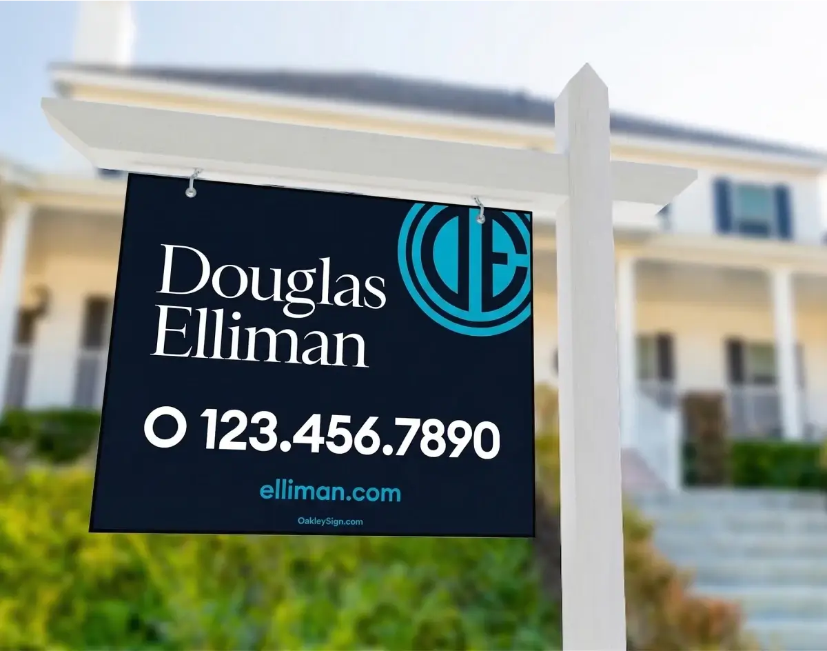 Douglas Elliman real estate for sale sign in navy blue with teal logo hanging from a white post in front of a colonial-style home