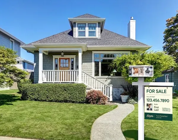 Keyes Realty for sale sign in front of gray craftsman bungalow with covered porch.