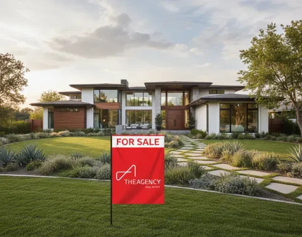 Modern luxury home for sale with a red The Agency Real Estate sign on a manicured front lawn
