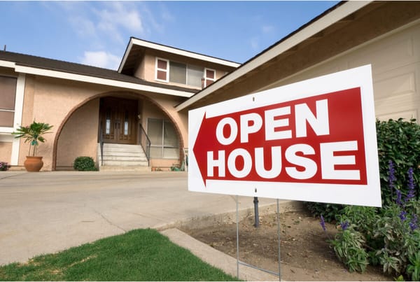 Red open house sign in front yard of home