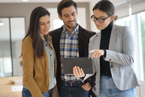 Realtor showing clients figures on a tablet.